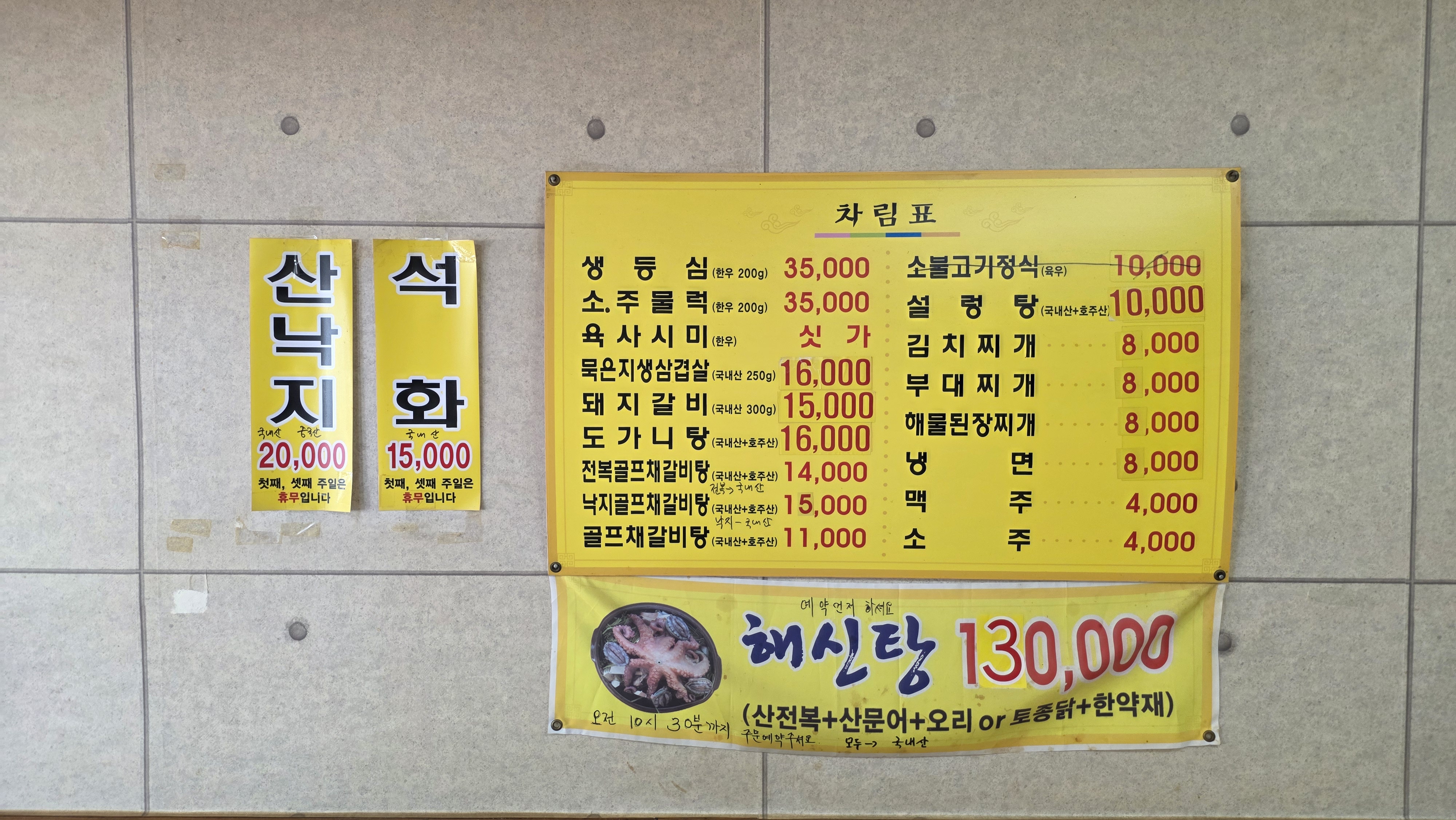 A yellow menu listing beef sirloin, pork ribs, soups and stews, with prices, weights and additional notices for sannakji, oysters and haesintang