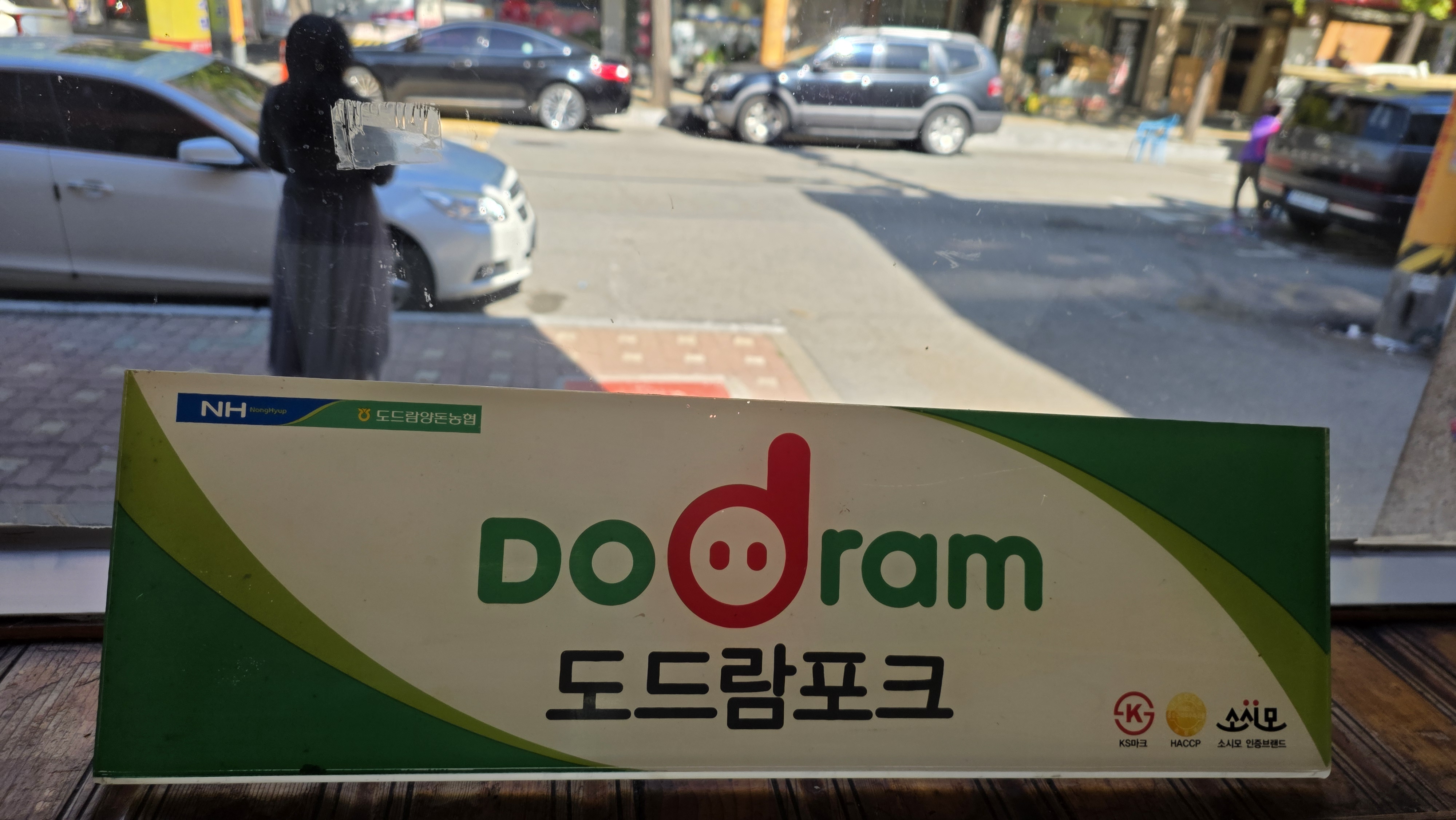 A sign bearing the Dodram Pork logo by the window