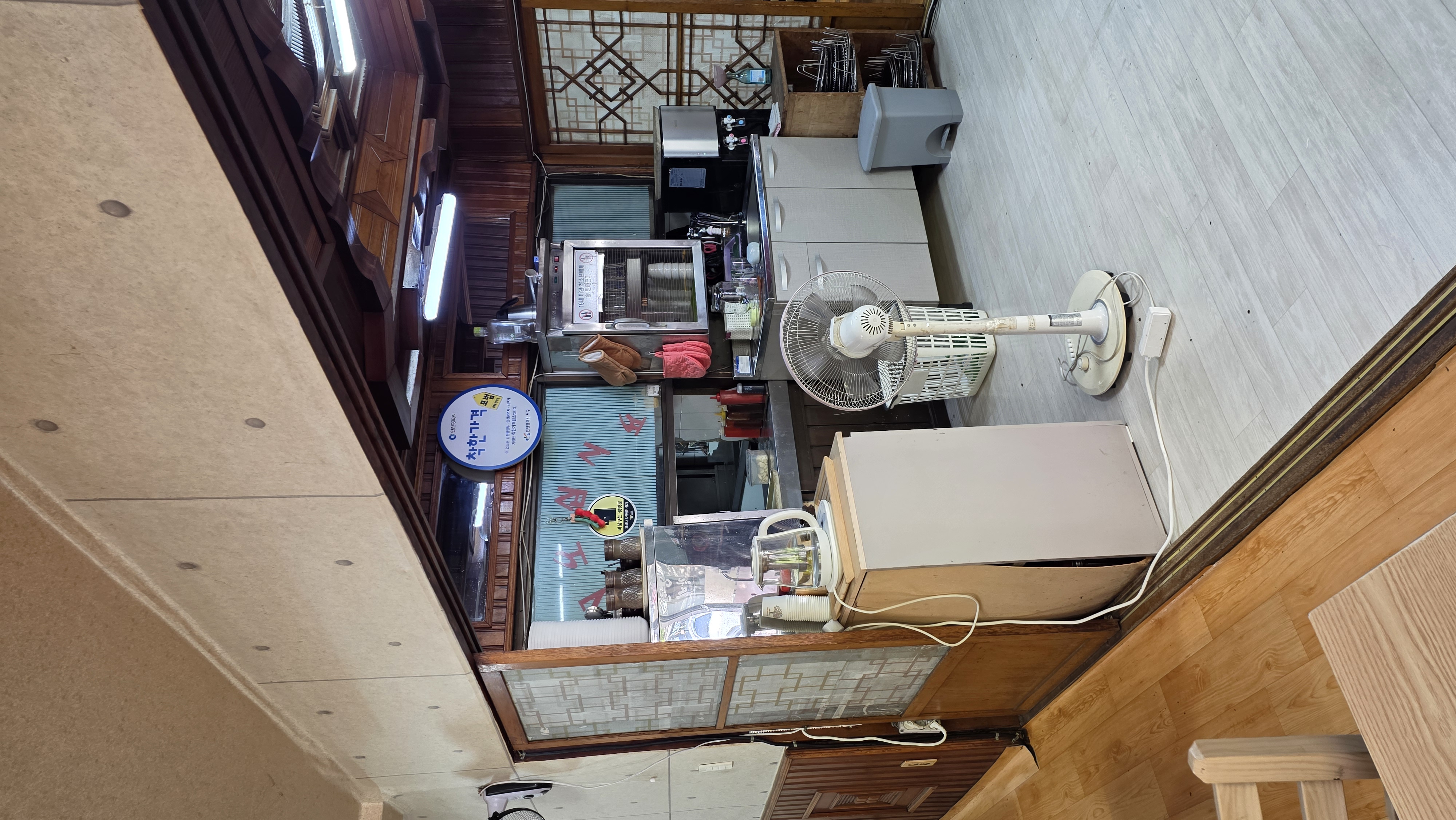 A dish-storage unit and a fan in front of the kitchen window, with a Good Price Business sign above