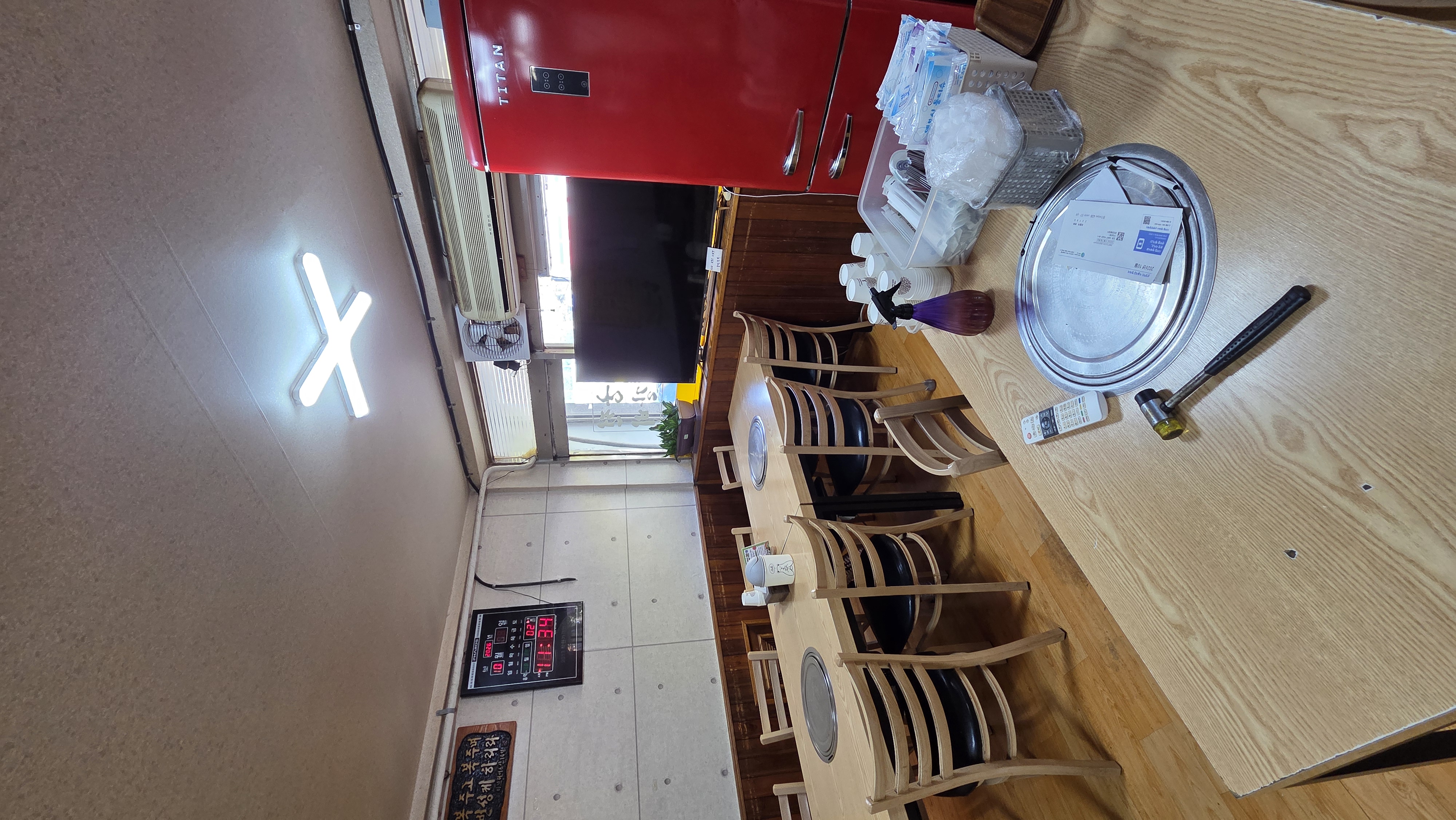 Wooden tables with round grilling braziers by the window, a television and a refrigerator
