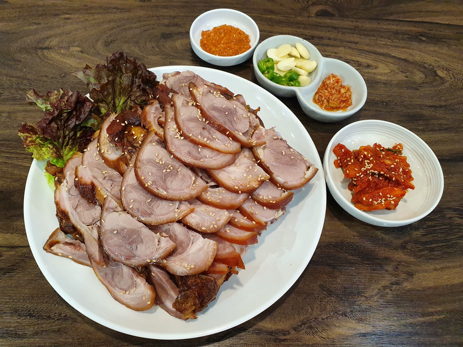 쌈 채소와 곁들임 반찬이 함께 놓인 족발 한 접시